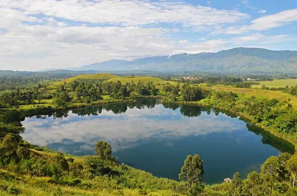 Scenic view of a reflective Crater Lake in Uganda surrounded by green hills, typical of the Western Rift Valley landscape